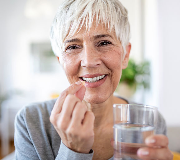 senior woman smiling while taking multivitamin
